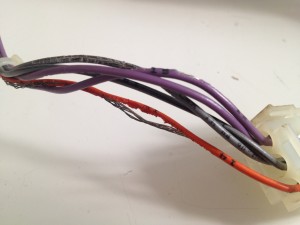 One of the wires sending 60VAC to the monitor via the I/O harness, showing mouse damage.
